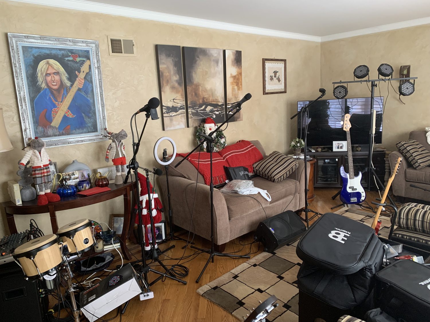 Living-room live space with a drum kit, couches, and guitars on the wall
