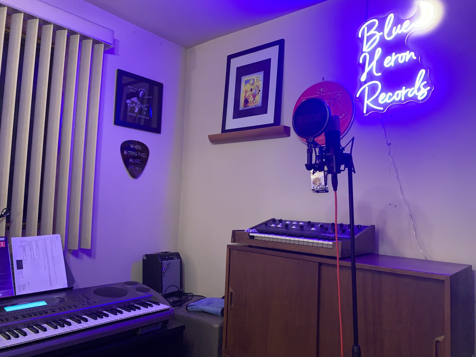 Small isolation booth with the Blue Heron Records neon sign and a condenser microphone