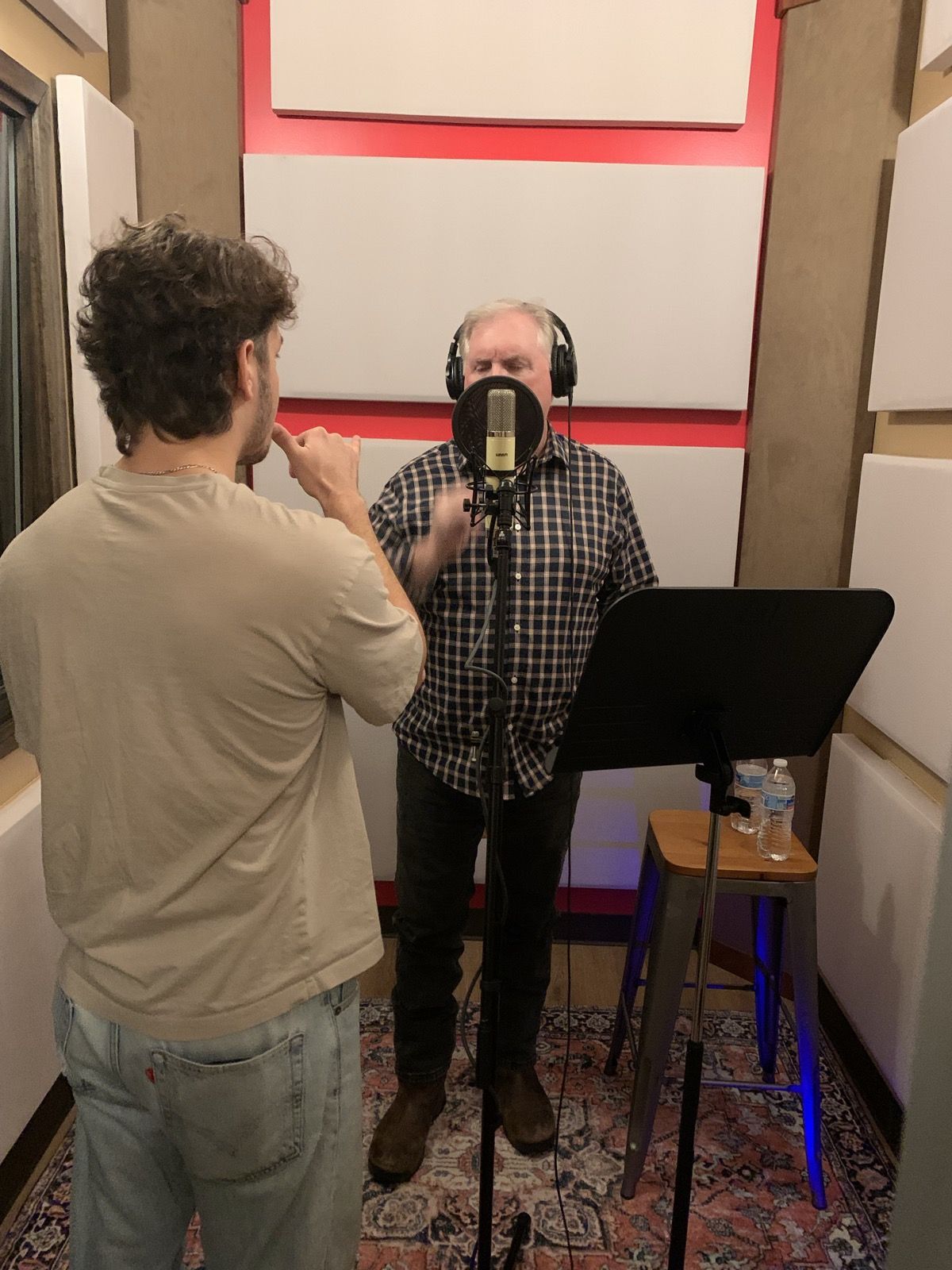 A vocalist at the microphone with an engineer.